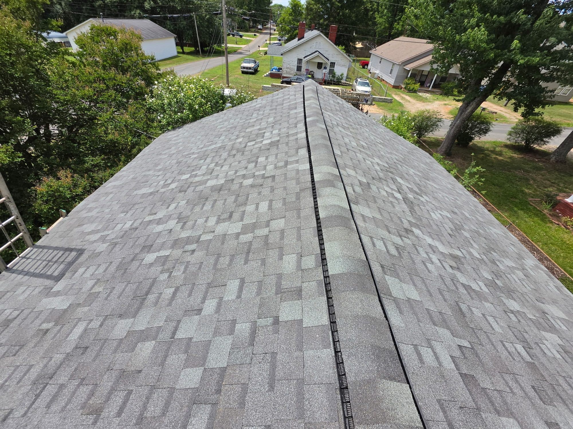 New gray asphalt shingle roof with ridge vent seen from above